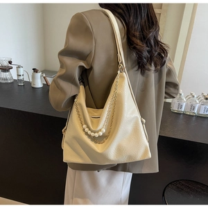Sac Hobo beige chic avec détails de perles et chaîne dorée présenté dans un décor de café