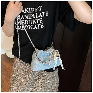 Detail of light blue denim bucket bag with silver bead chain and lace pearl fringe