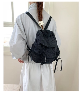 Détail du sac à dos à carreaux noirs avec cordon de serrage et bretelles réglables