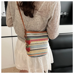 Détail du sac seau en paille tissée colorée avec charms fraises et bandoulière en cuir