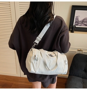 Detail of a beige nylon travel bag with adjustable strap shown in a lifestyle setting
