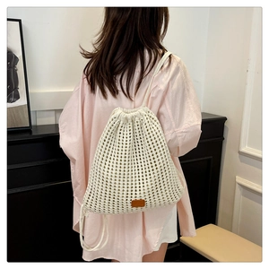 Detailed view of white knitted hollow flower drawstring backpack worn by a model