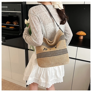 Détail du sac cabas en paille tissé avec rayures noires et bandoulière en cuir élégante