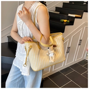 Close-up of yellow striped canvas tote bag with leather strap and puppy charm