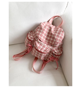 Gros plan d'un sac à dos en toile à carreaux rouges et blancs avec fermetures à nœuds