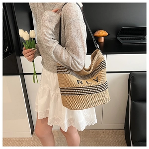 Dettaglio della borsa tote in raffia con ricamo RLY e manici in pelle nera