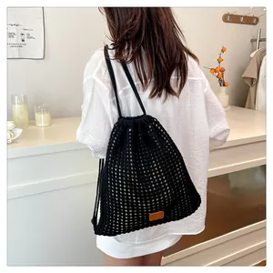 Close-up of black crochet mesh bucket backpack with drawstring and leather patch