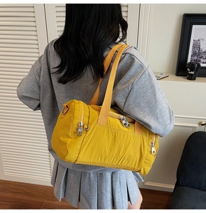 Shoulder view of a large yellow nylon travel duffel bag with textured fabric and metal zippers