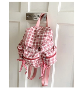 Détail du sac à dos à carreaux rose avec rubans rouges et poches zippées avant