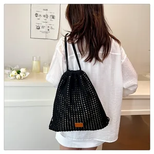 Close-up of black knitted mesh drawstring backpack on model in a minimalist setting