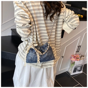 Detail of dark blue sequin bucket bag with pearl chain and cream lace bow detail