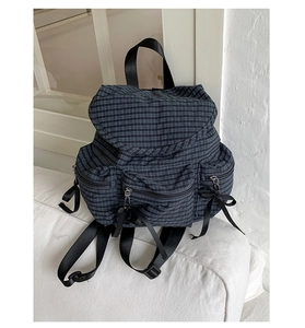 Détail du sac à dos en toile à carreaux avec nœuds en satin noir et poches zippées