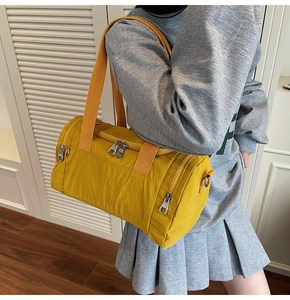 Detail shot of a yellow nylon gym bag with orange straps on shoulder in home setting