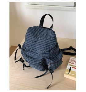Détail du sac à dos quadrillé avec doubles poches zippées et rubans noirs décoratifs