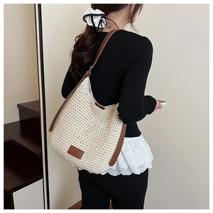 Close-up of cream woven hobo bag with brown leather shoulder strap and fashion label