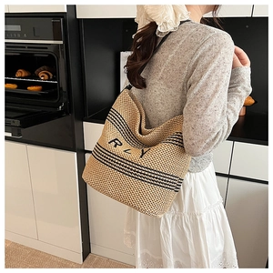 Dettaglio di una borsa in paglia beige a strisce nere e scritta RLY in una cucina