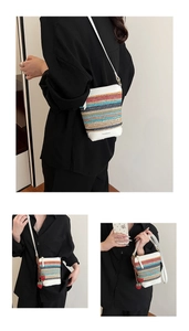 Detail of colorful striped woven bucket bag with leather strap and strawberry pendant