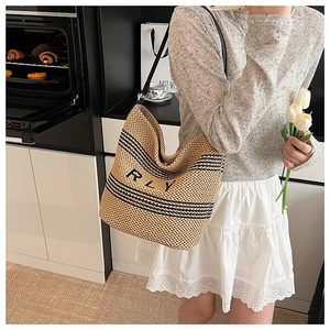 Gros plan d'un sac cabas en paille à rayures noires et lettrage RLY dans un décor de cuisine