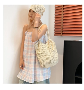 Detail of beige crochet tote bag featuring boho fringe and hollow-out woven texture