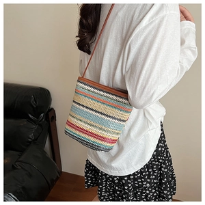 Détail du sac seau en paille tissée colorée montrant la texture rayée et la bandoulière
