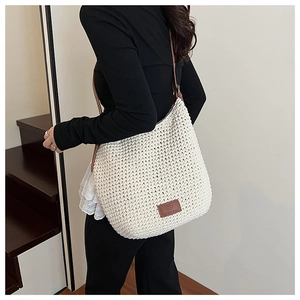 Detail of hand-woven cotton rope texture on beige tote bag with brown leather brand tag