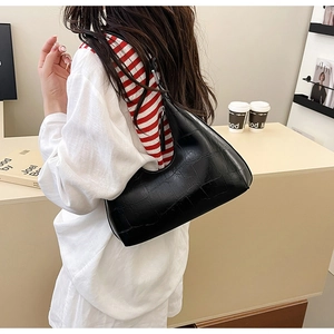 Detail of black crocodile pattern crescent hobo bag worn with elegant casual outfit