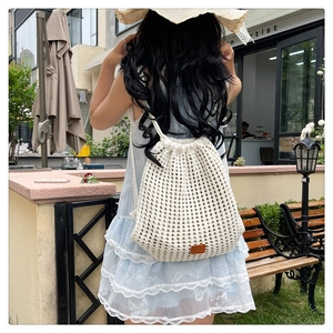 Close-up of white hand-woven mesh backpack with drawstring and brown leather patch