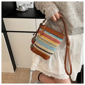Detail of woven bucket bag featuring colorful stripes and leather strawberry charms