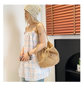 Detail of hollow-out woven straw tote with tassels for summer beach vacation styling
