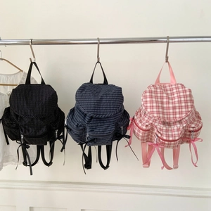 Trois sacs à dos en toile à carreaux avec nœuds en noir, bleu marine et rose sur fond blanc