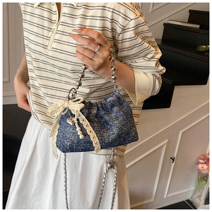 Detail of denim bucket bag with silver ball chain and pearl lace bow charm