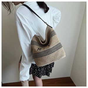 Close-up of beige woven bucket bag with black stripes and slender leather shoulder straps