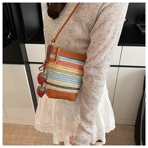 Vue détaillée du sac seau tissé arc-en-ciel avec finitions cuir et breloques fraises