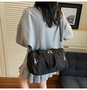 Detail of a black nylon crossbody bag with adjustable strap and dual zipper closure