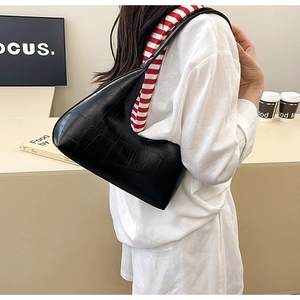 Detail of black crocodile pattern shoulder bag with glossy finish and moon shape