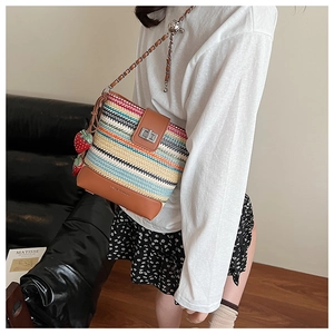 Close-up of bohemian woven bucket bag with leather base and strawberry charm detail