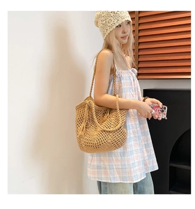 Close-up of a woven straw tote bag with intricate crochet texture and tassel detail