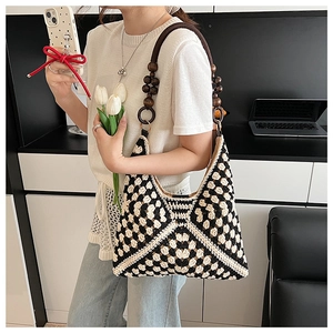 Detailed macro view of black and white checkered knit bag with wooden bead handle
