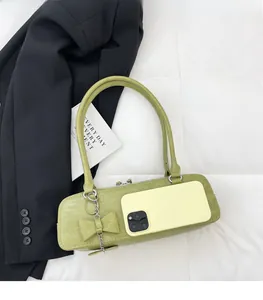 Sac hobo vert à motif crocodile avec charm nœud montrant la capacité pour téléphone