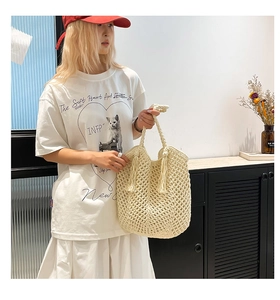 Detail of hand-woven hollow straw tote bag with long tassels for summer beach vacation