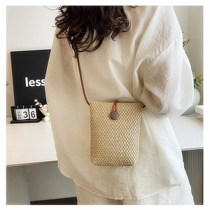 Detail of handwoven straw mini crossbody bag with button closure on a model