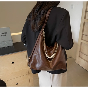 Détail du sac à bandoulière en similicuir marron avec chaîne dorée et perles décoratives