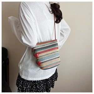 Détail du sac seau en paille colorée avec breloques fraises rouges et bordure cuir