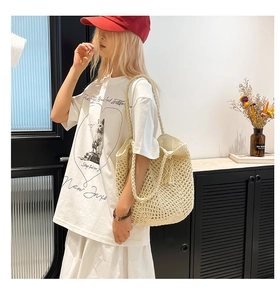 Close-up of a cream woven straw tote bag paired with a printed white casual t-shirt