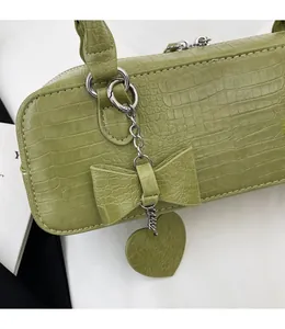 Détail du sac à main vert fruit à motif crocodile avec son pendentif noeud amovible