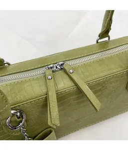 Détail du sac vert en cuir crocodile avec double fermeture éclair et rivets argentés