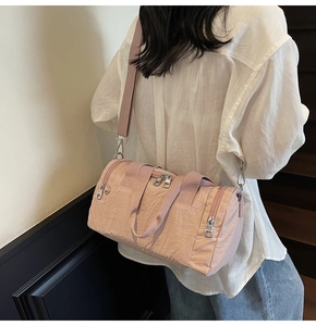 Detailed view of pink nylon bucket bag featuring side zippers and adjustable strap