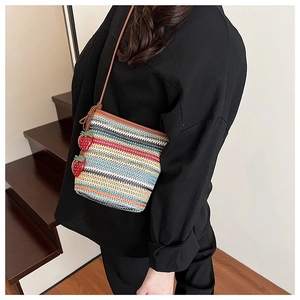 Détail d'un sac bandoulière en paille à rayures colorées et breloques fraises