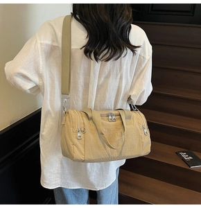 Detail view of khaki nylon travel bag featuring wide shoulder strap and multi-pocket design