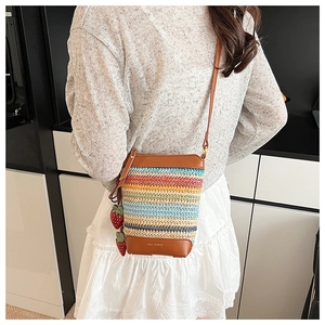 Detail view of woven bucket bag with colorful stripes and strawberry ornaments